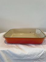 Front side view showing the orange exterior and cream interior with some stains and marks.