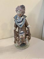 Front view of clown figurine showing facial expression, clothing, and dogs.
