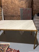 Overview of rectangular white marble coffee table with brass frame and legs.
