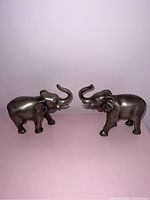 Front side view of the pair of pewter elephant bookends showing detail of raised trunks and body features