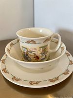 Cup inside shallow bowl inside plate, showing the concentric arrangement and bunny border design