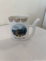 Front view of small antique ceramic vase with colorful Karlovy Vary scene and gold trim.