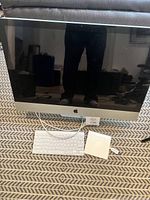 2011 27-inch Apple iMac desktop computer with wired Apple keyboard and power adapter on patterned surface.