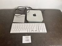 Photo showing the 2012 Mac Mini, Magic Trackpad, Apple keyboard, and power cable on a textured surface