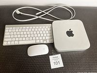 Full lot image showing Mac Mini, keyboard, and mouse from above on black textured surface.