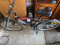Full side view of the black and red Supercycle SGS 600 mountain bike with suspension and knobby tires showing pedals and saddle.
