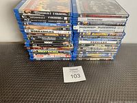 Stack of 30 Blu-ray movie cases showing titles such as The Expendables 2, The Big Lebowski, Wonder Woman, Transformers, Rocky Balboa and others.
