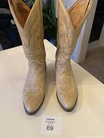 Front-top view of beige cowboy boots showing decorative stitching and pointed toes.