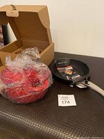 Open box with visible set of red pots in plastic wrapping and Heritage Rock Diamond fry pan with packaging.