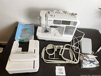 Top-down view of Brother embroidery machine with all accessories spread out including hoops, extension table, foot pedal, manual and accessory bag