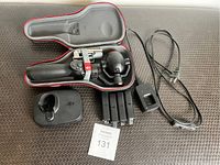 Photo of DJI Osmo Mobile handheld gimbal with attached smartphone mount inside open hard foam carrying case, three batteries lined up below, charging dock and power cable beside.