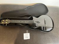 Black Enya ukulele in hard case with unique sound hole cutout design, pearl fret inlays, and gold tuning pegs.