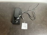 Single photo showing the Expressive E Touché SE MIDI controller pedal on a textured brown surface, alongside a tag marked '130'. The pedal is black with a foot pedal and a single control knob, USB cable attached.