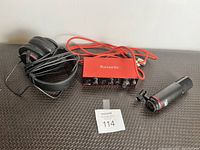 Audio interface, microphone, and headphones arranged on a textured black surface.