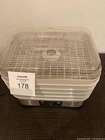 Full view of the food dehydrator showing the clear plastic lid and stacked trays.