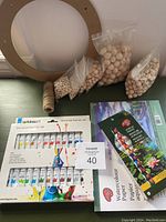 Lot contents including bags of wooden beads, twine, Kingart acrylic paint set, and watercolor paper pads on shelf.