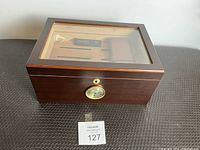 Closed view of the wooden humidor with glass top and analog hygrometer on the front.