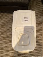 Top view of closed white plastic pet food container with sticker on lid and a small dispensing door