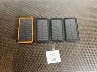 Four solar charged battery packs laid out on a textured surface, showing solar panel charging surface.