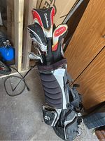 TaylorMade clubs loaded in Nike stand bag with legs extended in garage setting