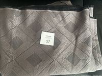 Grey geometric pattern fabric folded showing the full fabric piece with textured diamond shapes in grey shades.