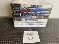 Stack of nine original Xbox game cases on a flat surface with a lot number card in front