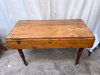 Front view of the wooden dining table with drop leaf extensions down
