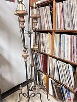 Two antique floor lamps standing next to a bookshelf, showing their full height and structure.