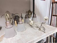 Four assorted wall sconces on table showing different styles and finishes.