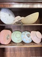 All six lamp shades arranged on a wooden shelf, showing colors and visible details.