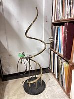 Spiral brass floor lamp with black round base and two light sockets, front view