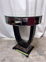 Full view of the semi-circular mirror accent table with reflective panels on the top rim and a black U-shaped base.