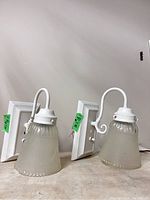 Pair of vintage white wall sconces with frosted etched glass shades and white metal mounts from two angles.