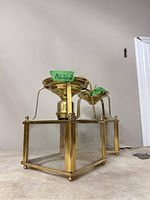 Two square brass and glass pendant lights shown from a low angle to display brass frames and etched glass panels.