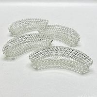 Four clear glass hobnail bone dishes shown stacked and laid out to display hobnail pattern and curved shape.