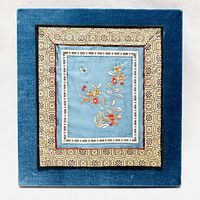 Front view of the Chinese embroidery framed artwork showing the intricate floral and bird motif in the center with blue and gold geometric frame.