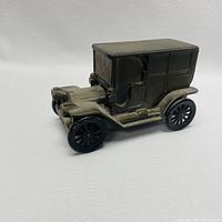 Front and side view of a cast metal Ford Model T bank showing detailed body and black spoked wheels
