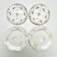 Top view of four Limoges porcelain plates, two with pink floral designs and two with beige floral scalloped edges