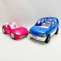 Front view of pink convertible and blue and white SUV toy cars with Barbie license plate