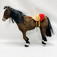 Full side view of plush brown toy horse with saddle and black mane and tail