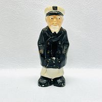 Front view of the vintage ceramic captain piggy bank with visible cracks and paint wear.