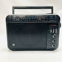 Front view of the vintage GE Superadio radio, showing speaker grille, tuning dial, and carry handle.