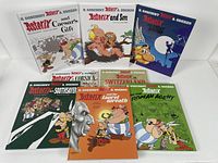 Eight Asterix comic books displayed with colorful illustrated covers showing various characters and scenes from the comics.