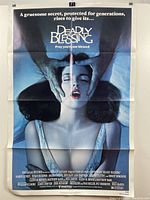 Full view of the "Deadly Blessing" vintage movie poster showing image of a woman's face with hands gripping her head and movie credits at bottom with fold lines.