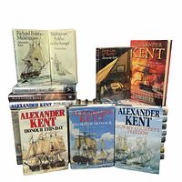 31 hardcover books by Alexander Kent arranged in two stacks and some standing, showing titles and cover dust jackets with naval sailing ship themes.