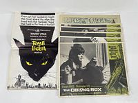 Set of vintage movie lobby cards and a merchandise magazine including 'Tomb of Ligeia' with a black cat graphic, 'Brides of Dracula' card, and 'The Oblong Box' cards stacked.