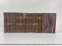 Photo of 13 volumes of Charles Dickens works, showing front marbled covers and leather spines with wear