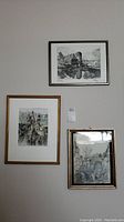 Overview of three framed signed prints on wall, showing varying sizes and styles of architectural and landscape art.