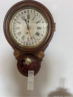 Front view of antique calendar clock showing dial, numerals, hands, calendar days, and pendulum case.