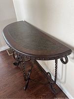 Angled side view capturing the semi-circular shape of the table and rivet detailing along the top edge.